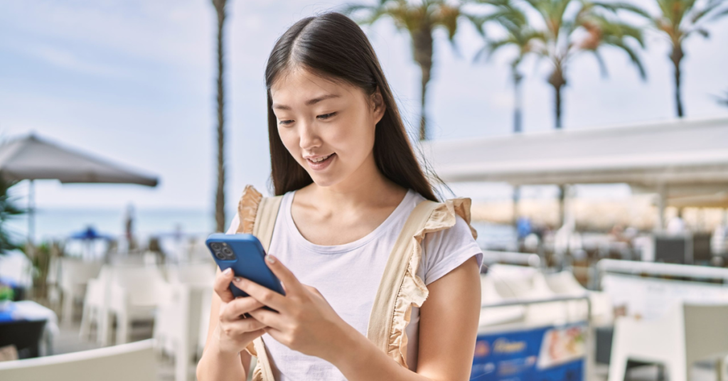 Young person smiling happy using smartphone at the promenade.