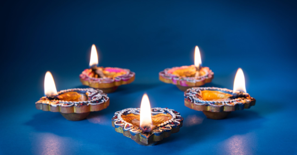 Lit Clay Diya lamps, blue background