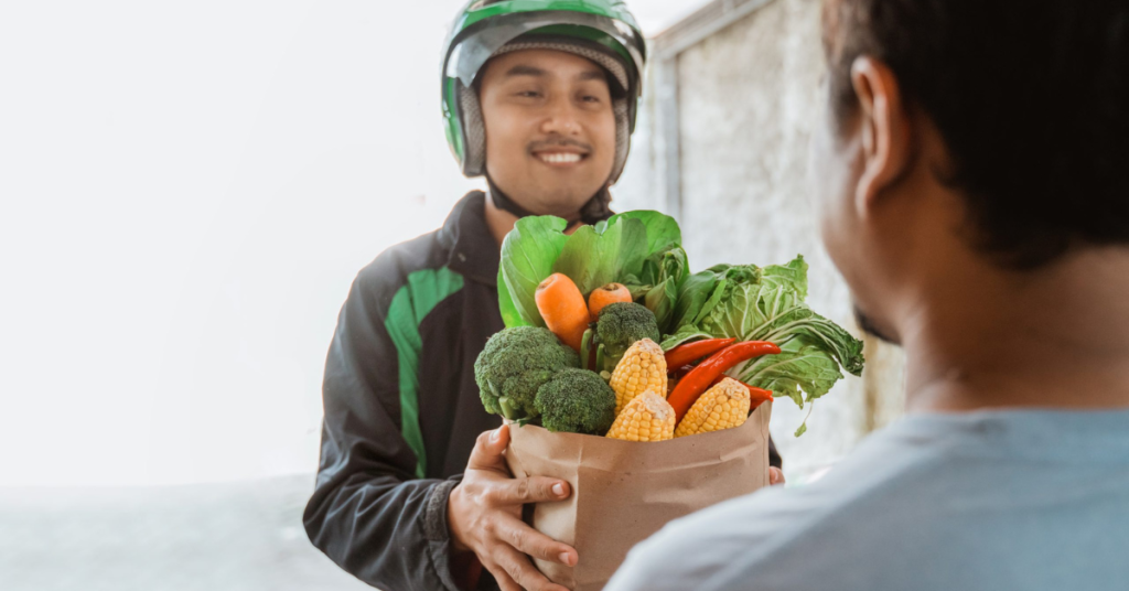 portrait of a smiling courier delivering online grocery shopping to customer at home