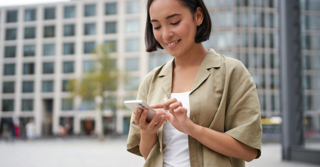 Person outside, smiling and going through phone