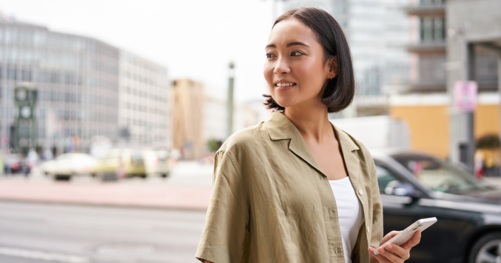 young woman walking around city holding phone