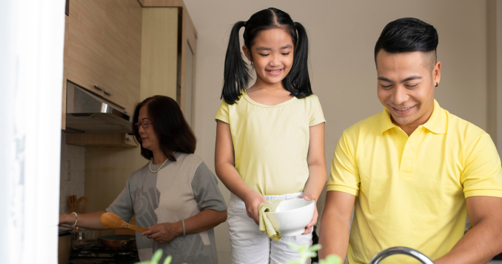 Family of three in the kitchen, cooking and washing dishes