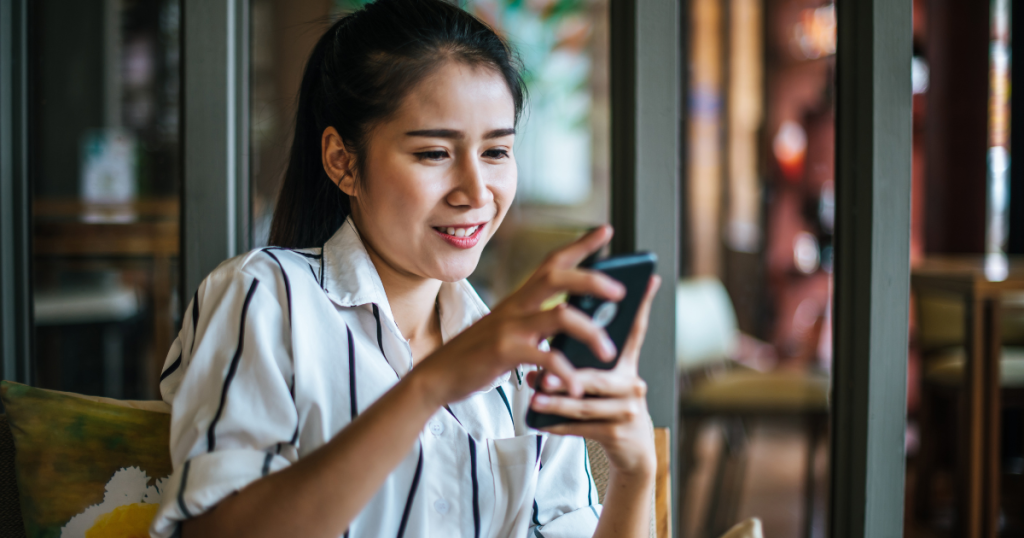 Woman sitting in a cafe patio going through her phone