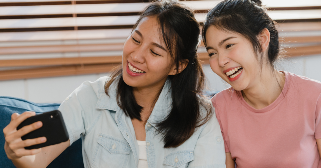 Two girls smiling and taking picture on phone