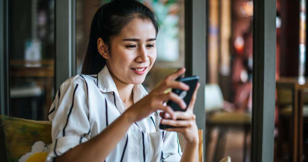 Lady sitting in a cafe, on her smartphone, Sending Money to the Philippines