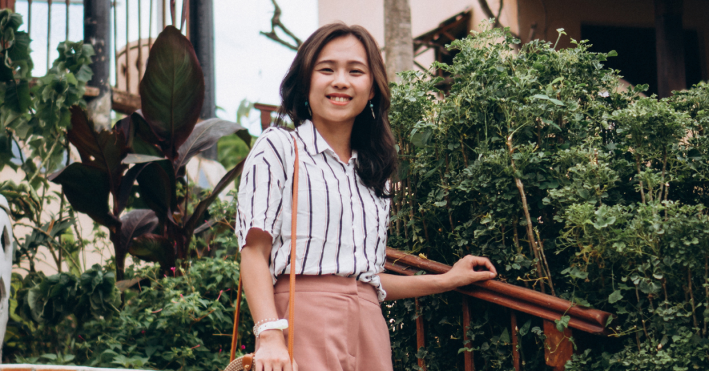 smiling asian woman posing outside halfway up stairs