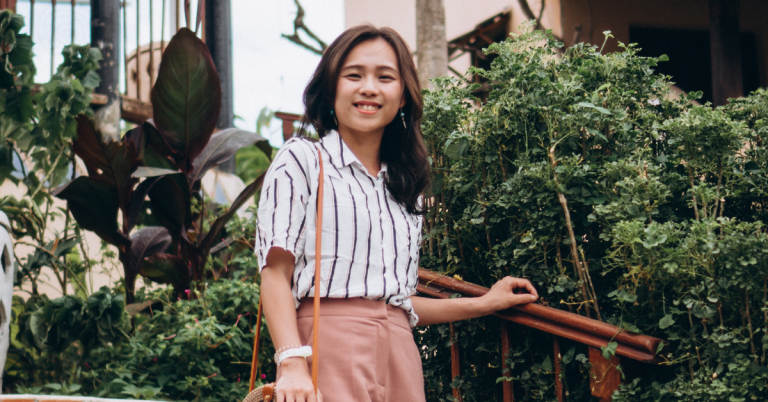 smiling asian woman posing outside halfway up stairs