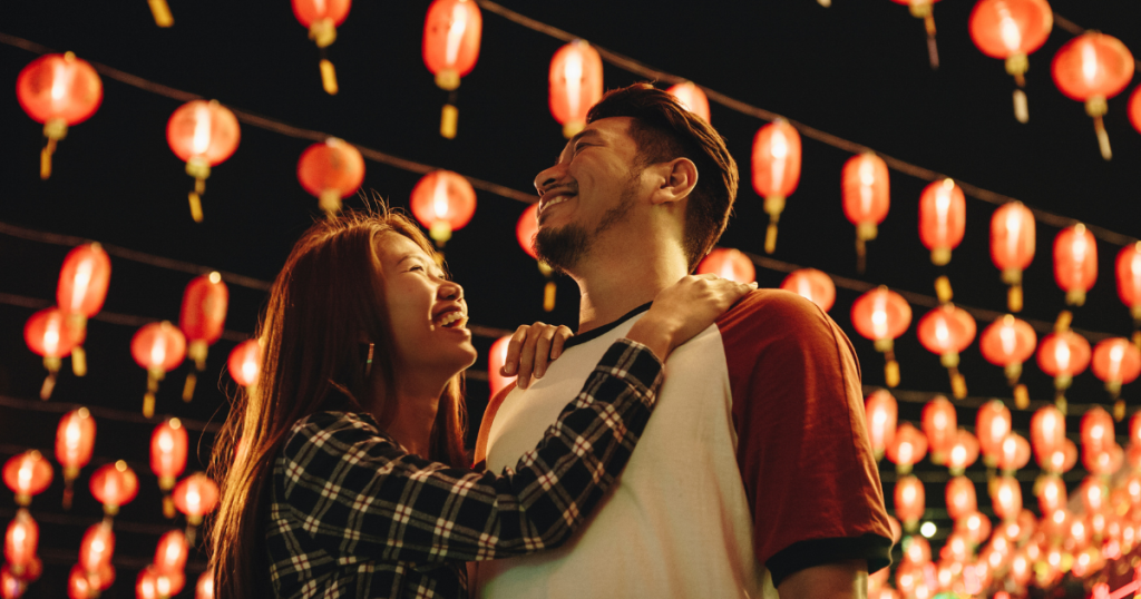 Young couple embracing and looking up at a night sky of lanterns