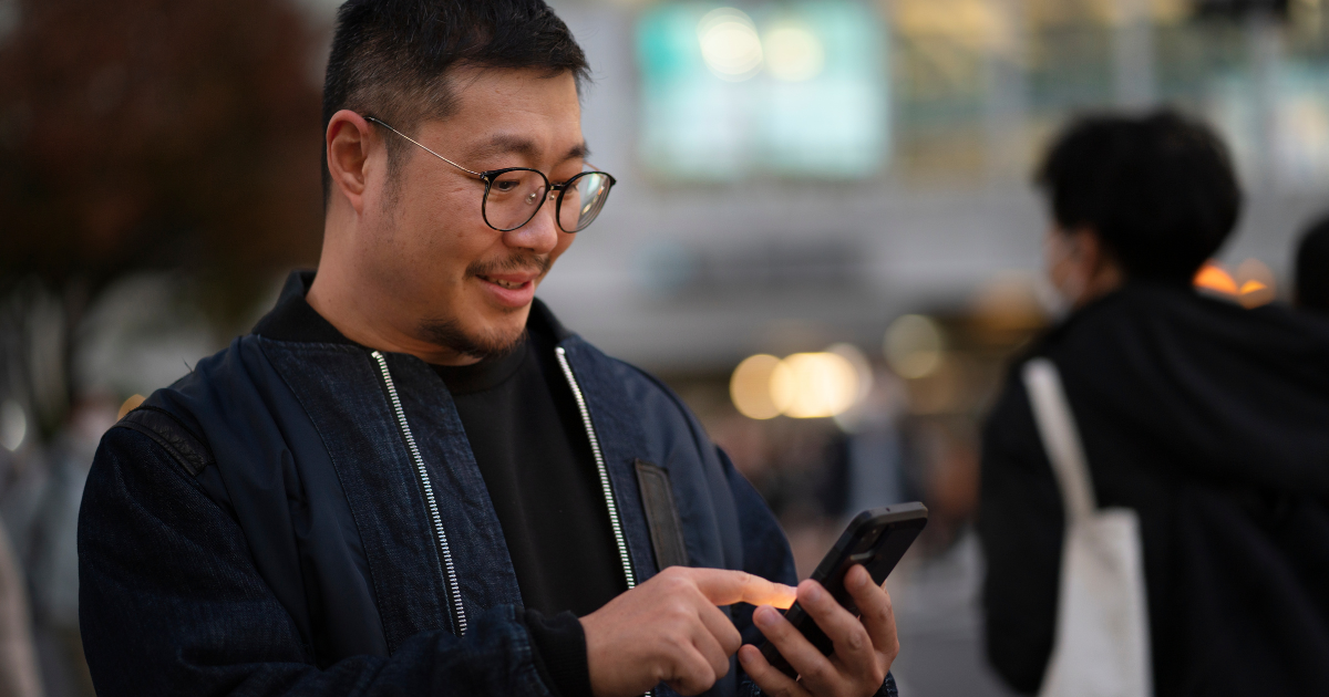 send remittance: Man on his phone, outside, smiling