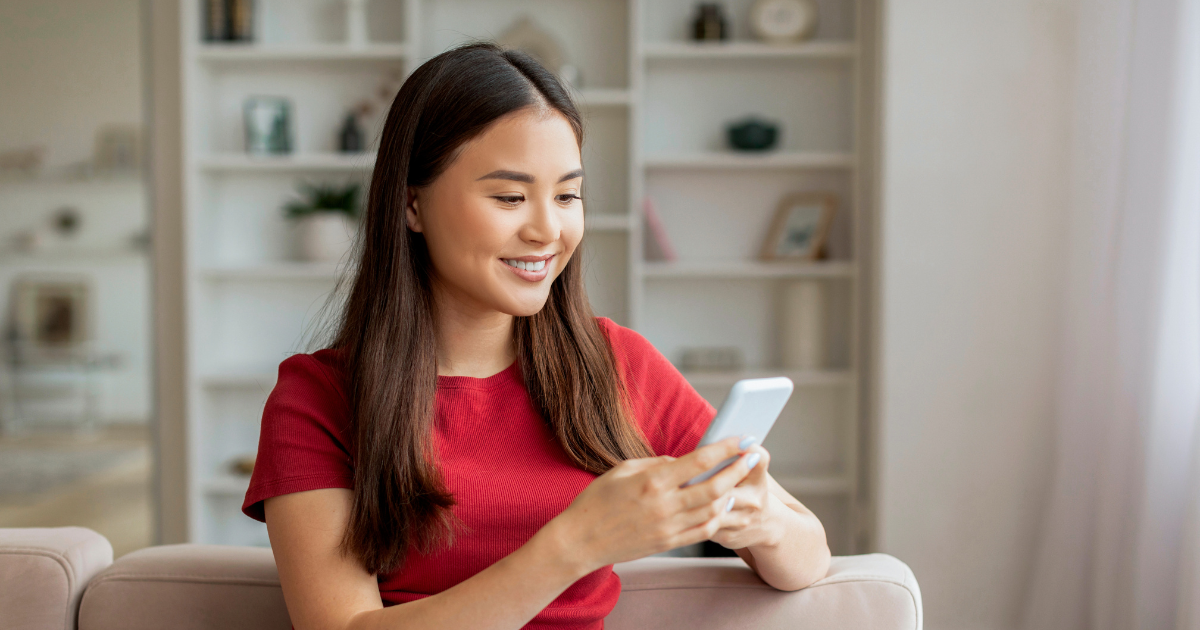 send remittance: Lady on her phone, sitting on the couch and smiling