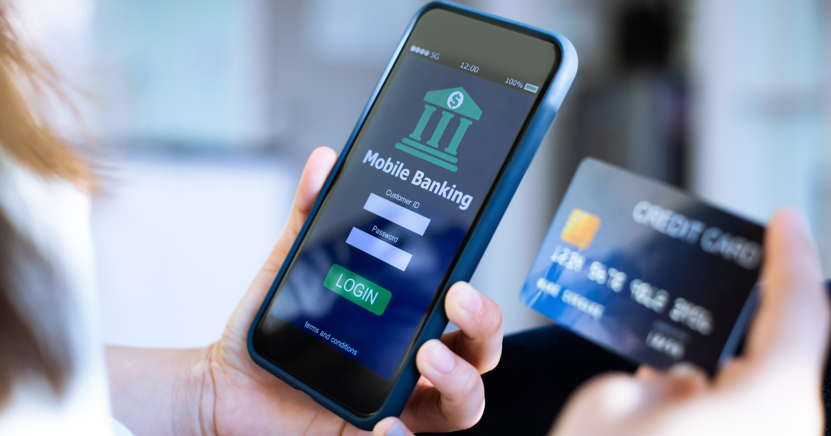 closeup of someone holding their smartphone in one hand with the screen opened to an online baking app, while holding their credit card in another hand