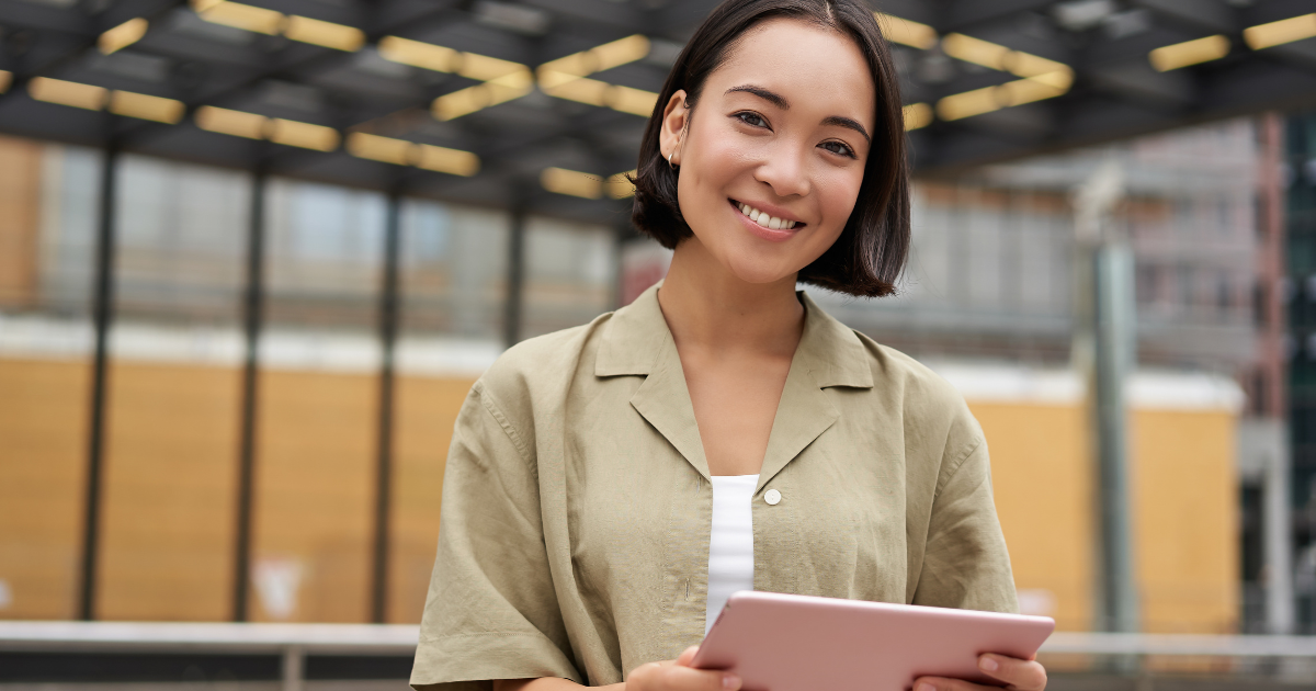 Smiling lady outside, holding a pink tablet