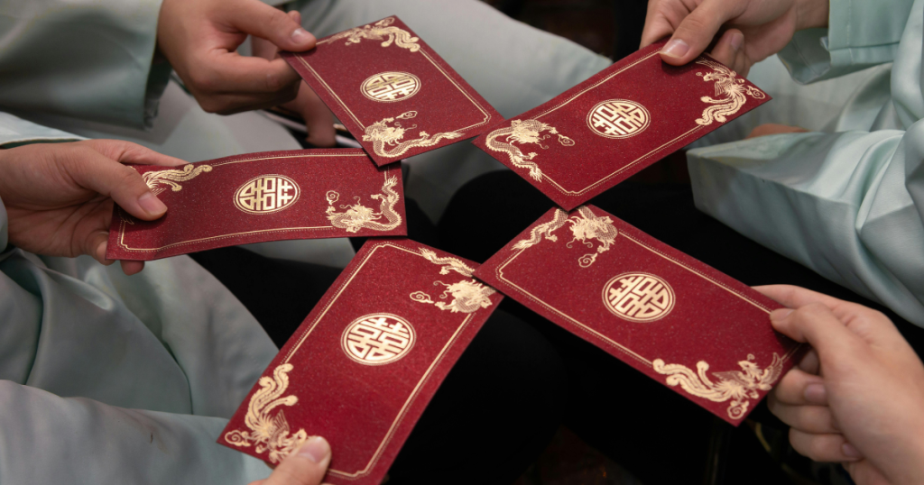 Closeup of a group people in a circle holding out red envelopes