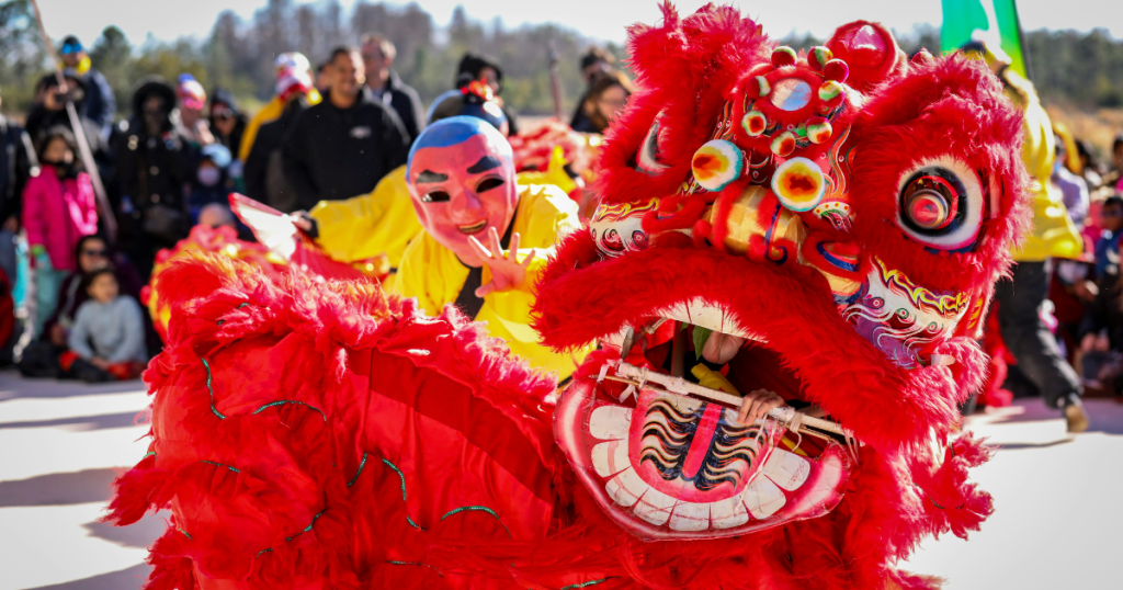 Lunar New Year Celebration outdoors with dancers in a Chinese lion costume performing, crowd watching them from behind